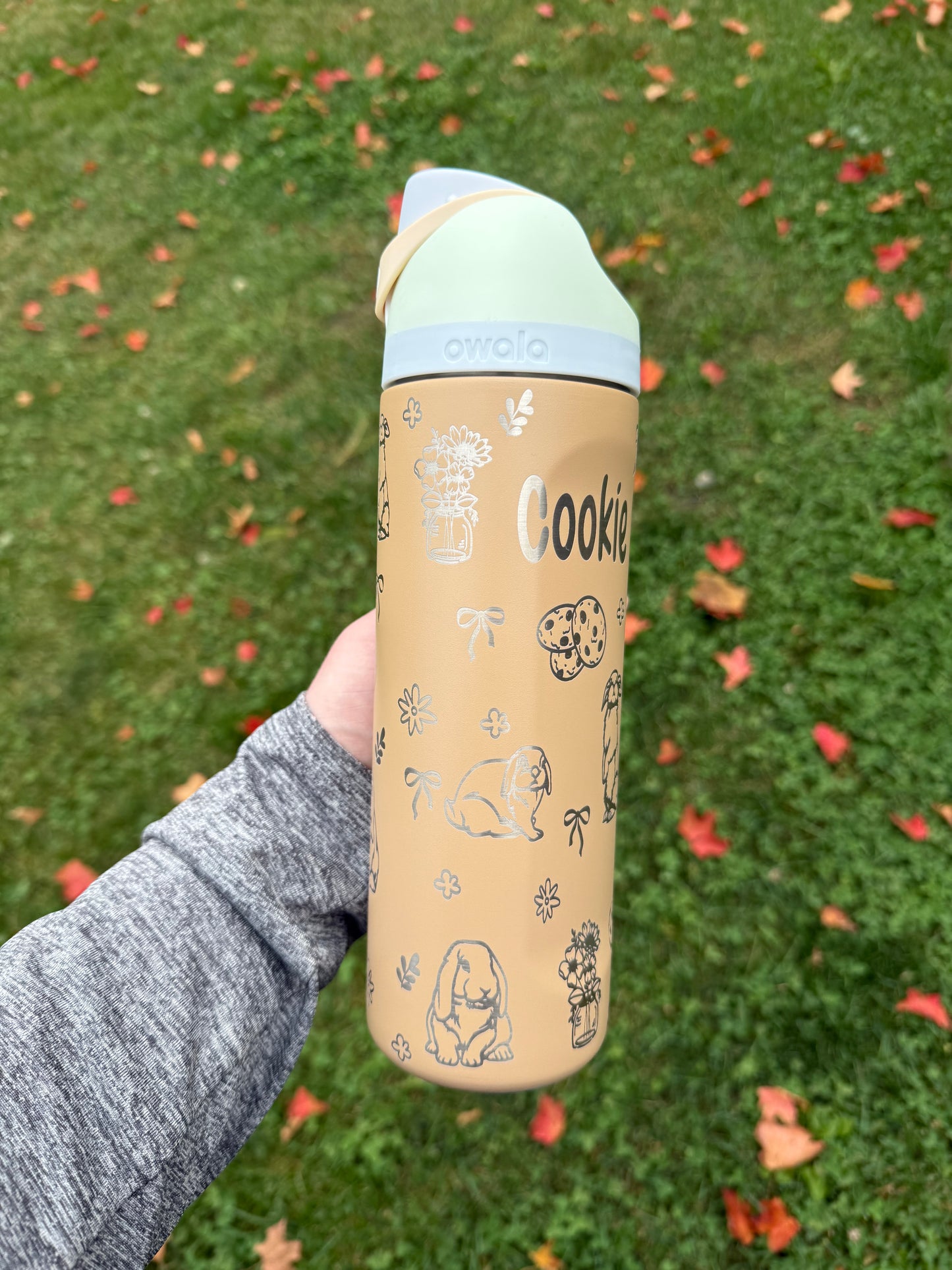 Person holding a cylindrical product with a patterned design against a grassy background