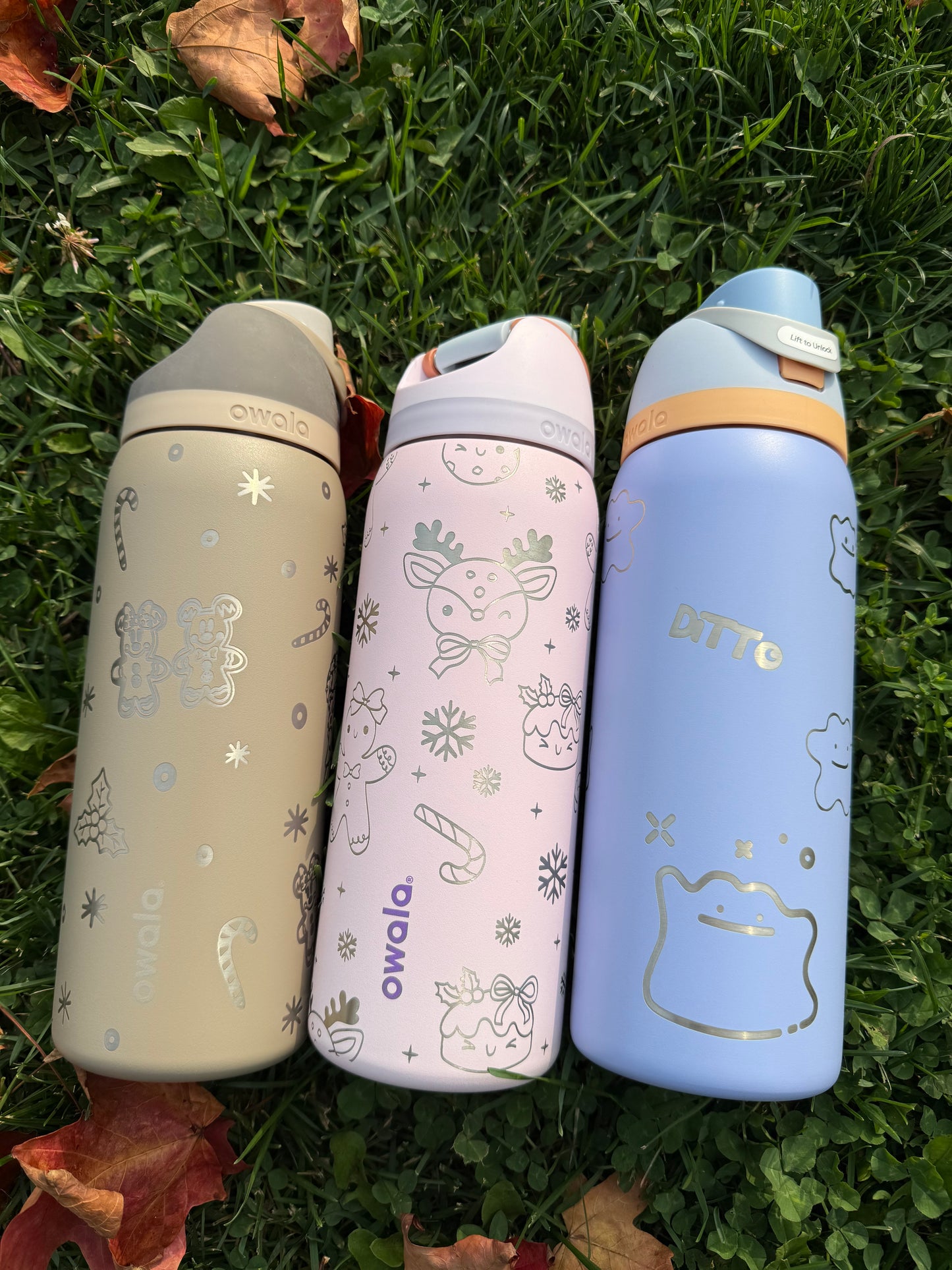 Three insulated bottles with cartoon designs on a grass background