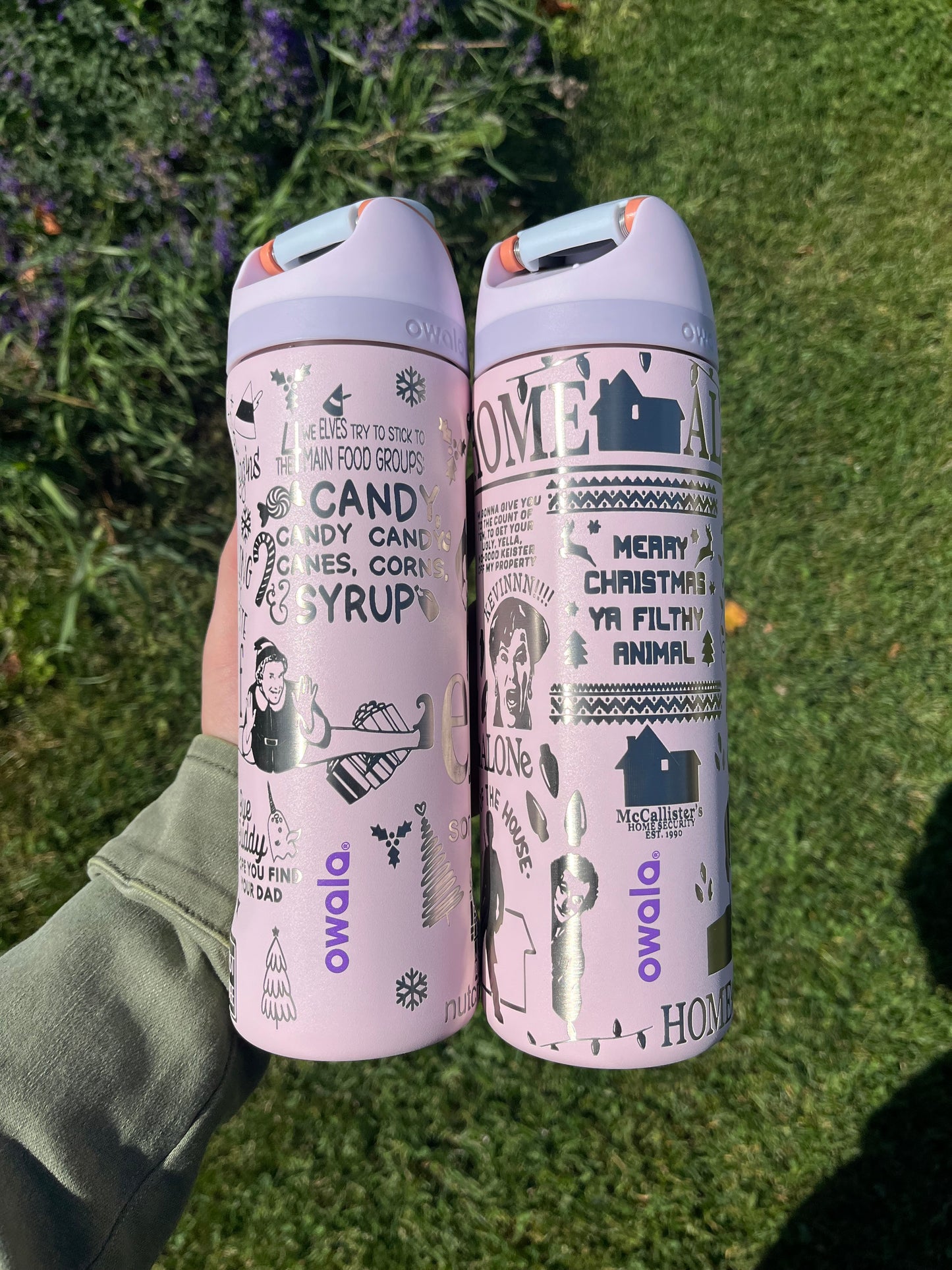Two pink cylindrical products with text and graphics on a grassy background
