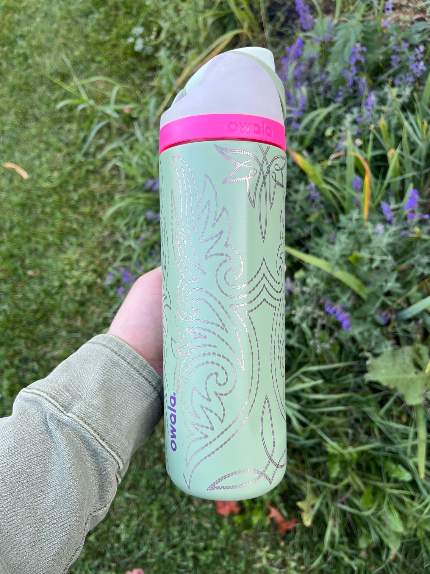Green and pink cylindrical container held in a hand with a natural background