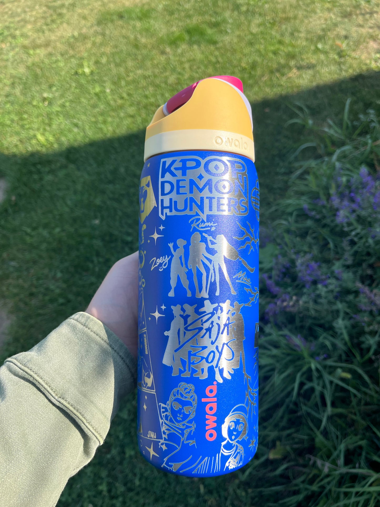 Blue water bottle with white graphics held by a person outdoors