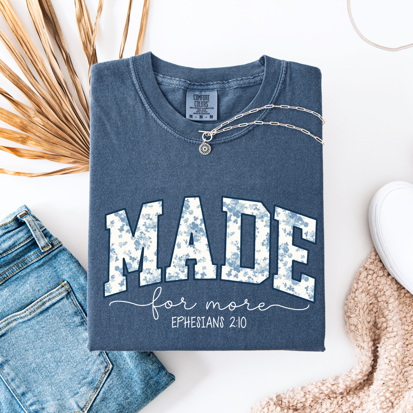 Blue t-shirt with 'MADE for more Ephesians 2:10' text, paired with jeans and a necklace on a white background.
