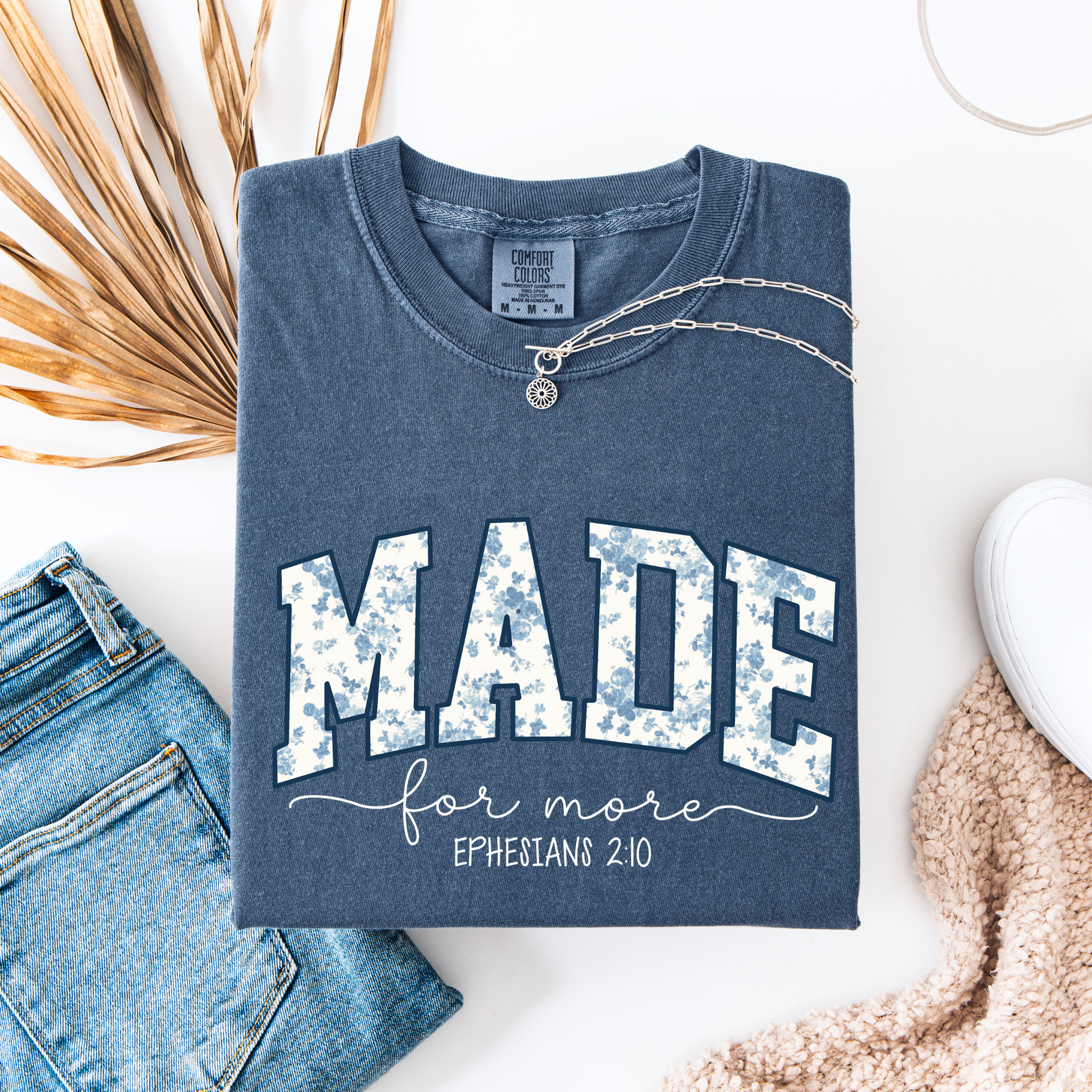 Blue t-shirt with 'MADE for more Ephesians 2:10' text, paired with jeans and a necklace on a white background.