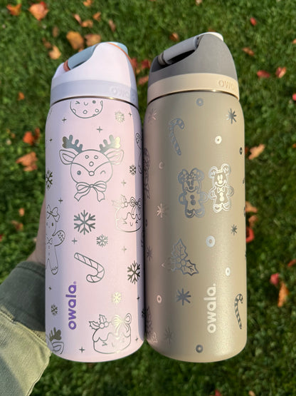 Two Owala water bottles with winter-themed designs on a grass background