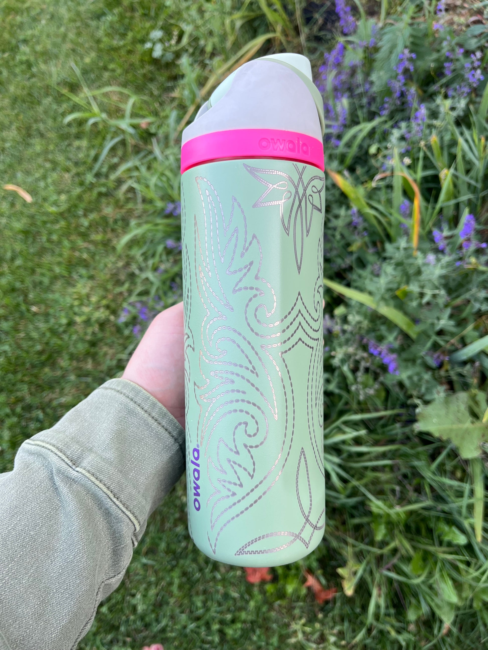 Green and pink cylindrical container held in a hand with a natural background