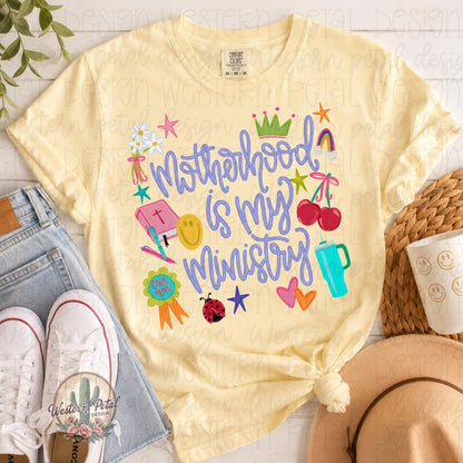 Comfort Colors 1717 butter yellow t-shirt mockup featuring colorful “Motherhood Is My Ministry” graphic with cherries, flowers, rainbow, Bible, tumbler, stars, and playful doodles in trendy coquette style.