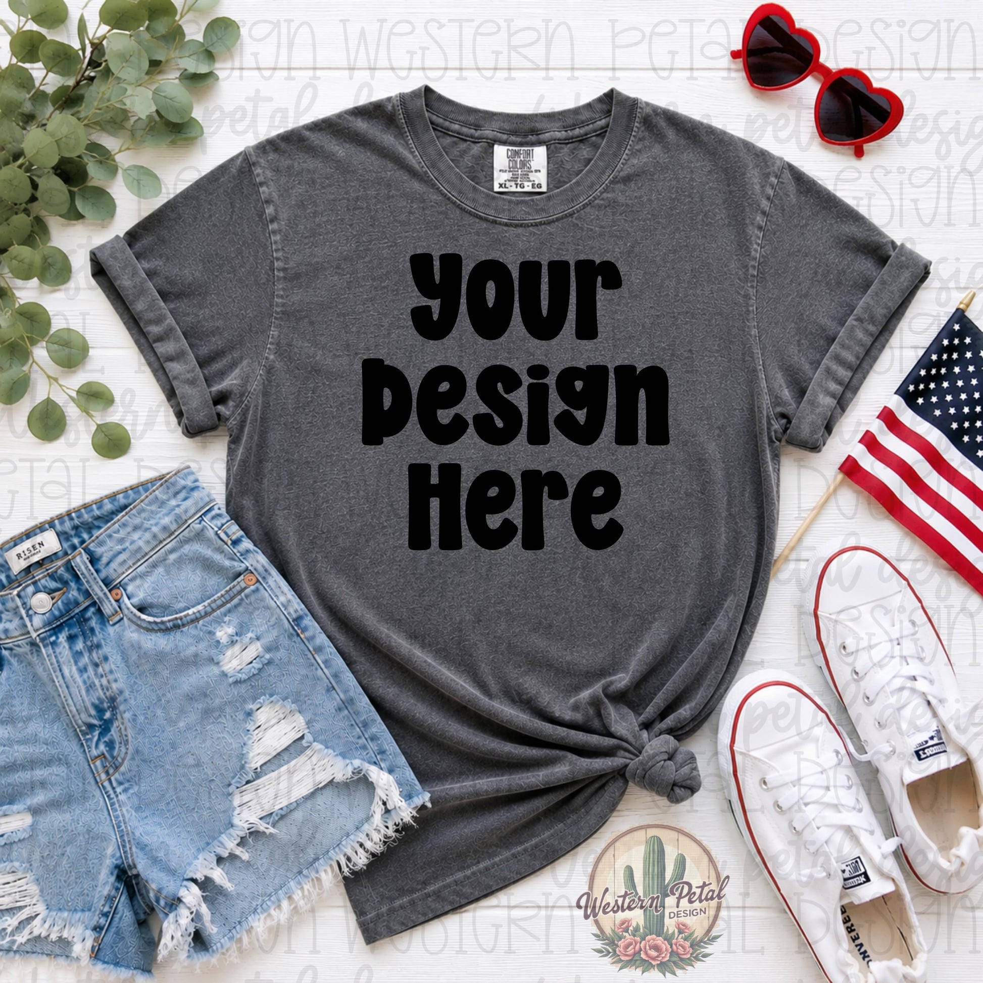 Comfort Colors pepper gray t-shirt mockup with distressed denim shorts, white sneakers, patriotic American flag, and heart sunglasses styled in a flat lay for Fourth of July shirt designs.