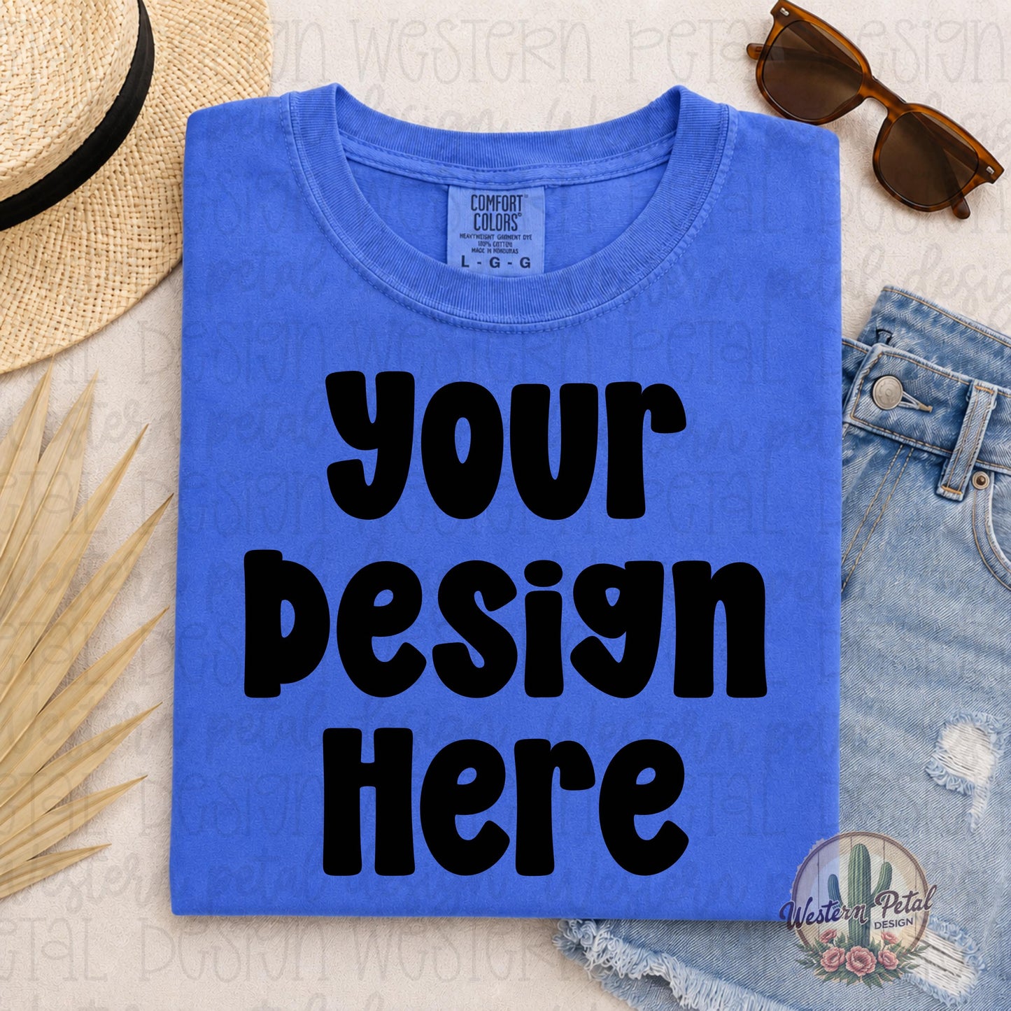 Comfort Colors Flo Blue blank t-shirt mockup in a styled summer flat lay with denim shorts, sunglasses, straw hat, and neutral beach-inspired accessories.