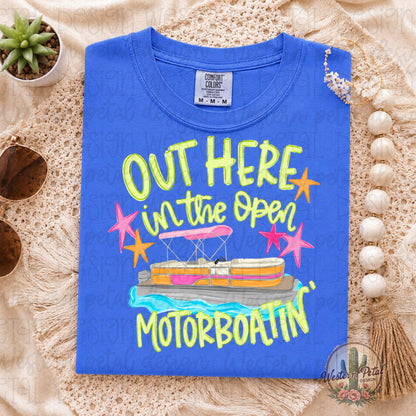 Bright flo blue Comfort Colors t-shirt with colorful “Out Here in the Open Motorboatin’” lake life graphic folded in a neutral summer flat lay setup.