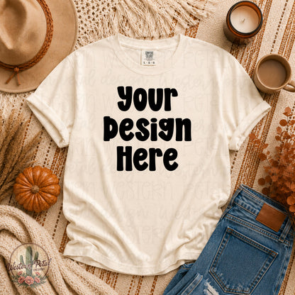 Comfort Colors ivory t shirt mockup styled in a cozy fall flat lay with pumpkins, denim jeans, candles, warm boho textures, and autumn decor.