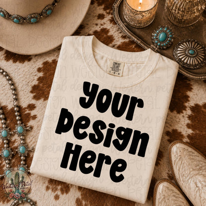 Ivory Comfort Colors folded shirt mockup styled on brown cowhide rug with turquoise western jewelry cowboy hat and candle decor