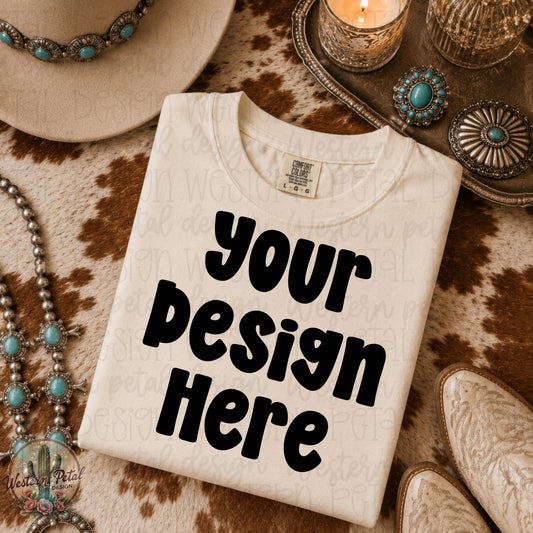 Ivory Comfort Colors folded shirt mockup styled on brown cowhide rug with turquoise western jewelry cowboy hat and candle decor