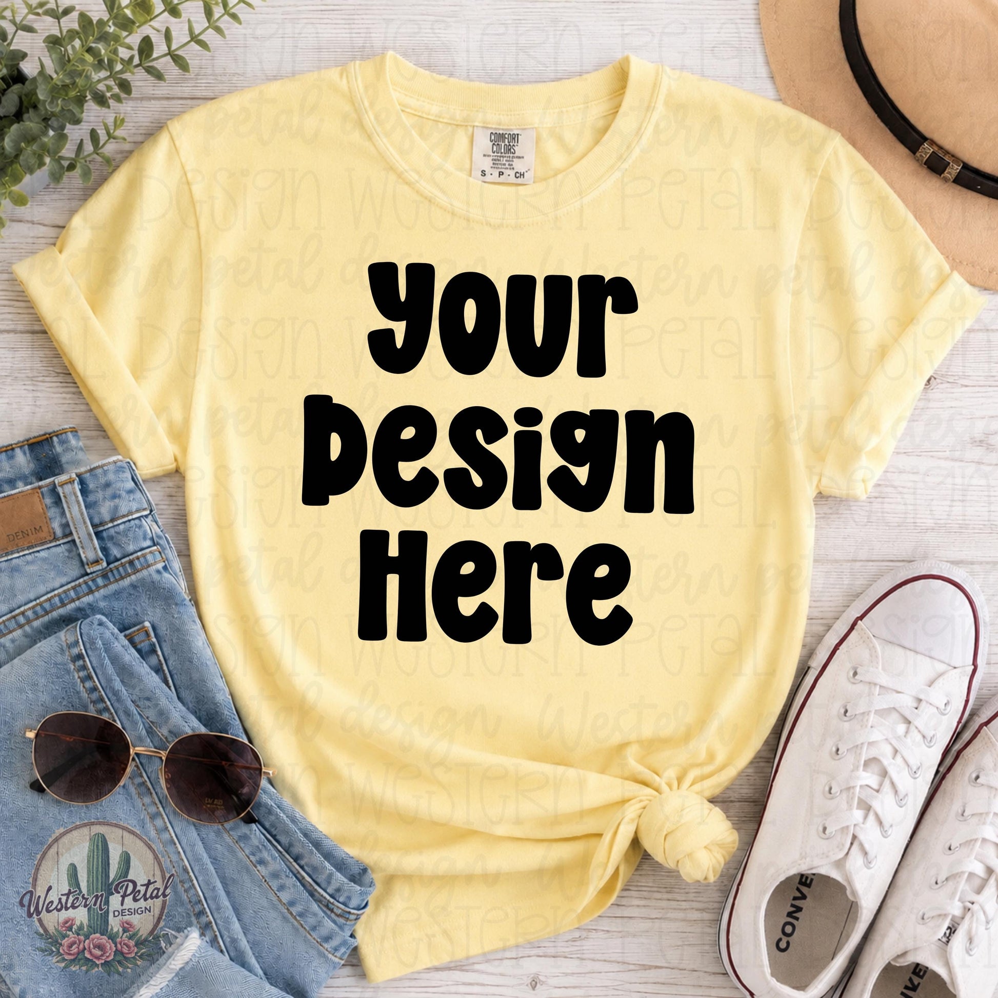 Blank Comfort Colors 1717 butter yellow t-shirt mockup with rolled sleeves and front knot styled with jeans, sunglasses, sneakers, greenery, and tan hat on white wood background.