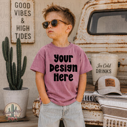 Little boy wearing a mauvelous Rabbit Skins t-shirt mockup standing in front of a vintage truck with western summer decor and sunglasses.