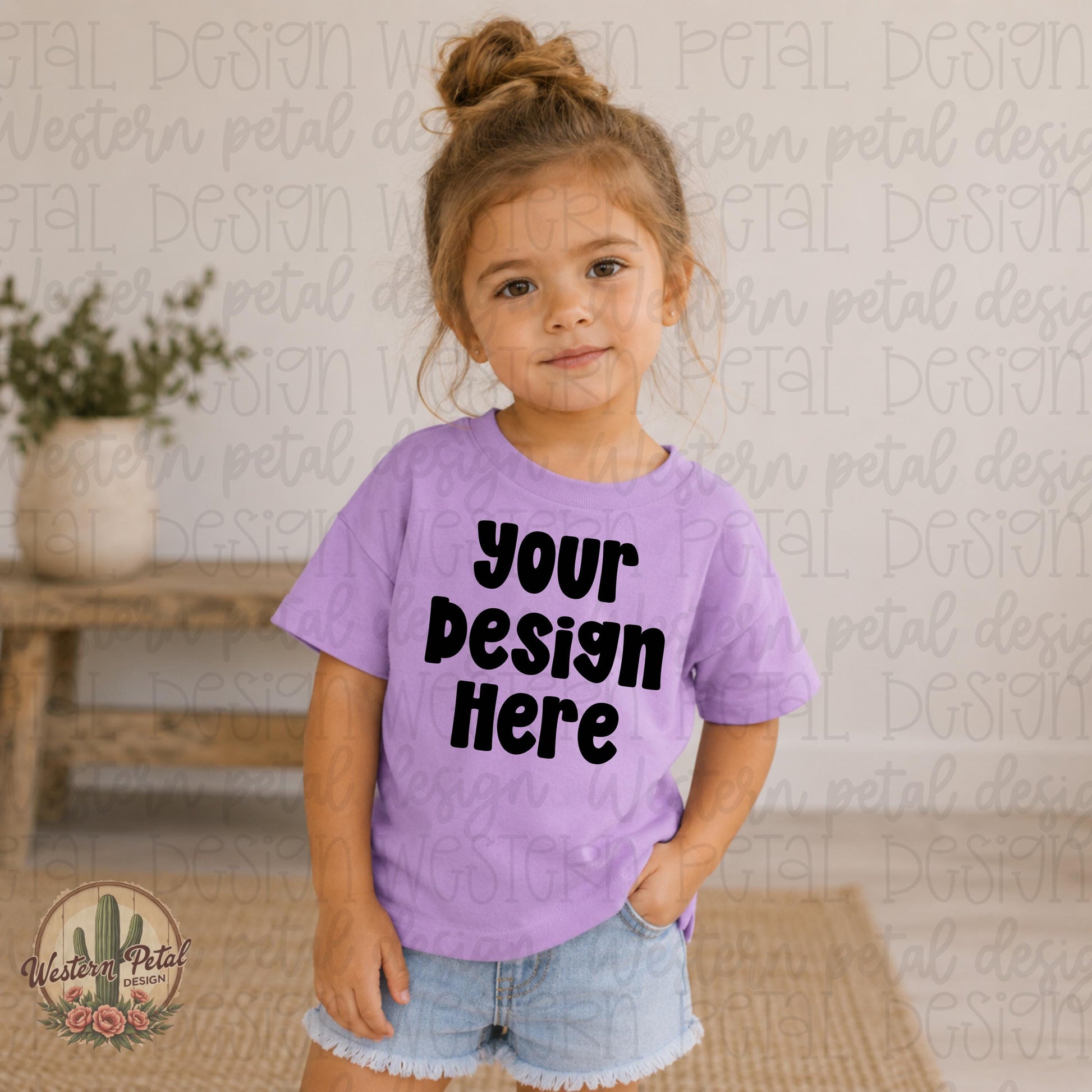Little girl wearing a lavender Rabbit Skins t-shirt mockup with denim shorts in a soft neutral indoor boutique setting.