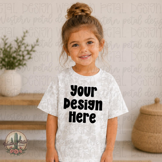 Smiling little girl wearing a Haze Tie Dye Rabbit Skins t-shirt mockup in a soft neutral indoor boutique setting.