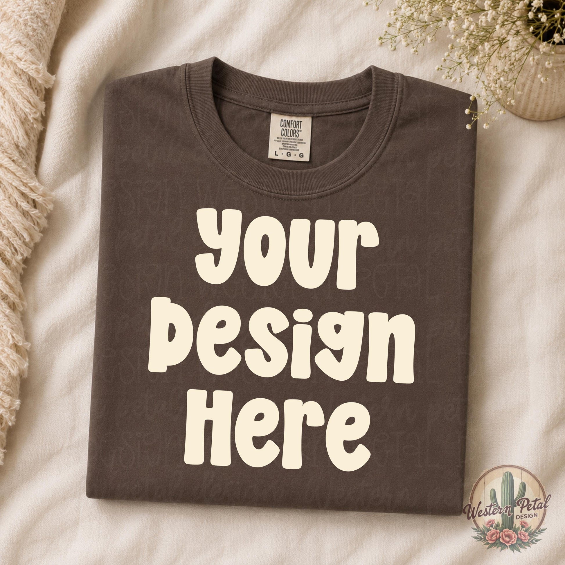Folded espresso brown Comfort Colors shirt mockup styled on cream bedding with neutral boho decor and soft feminine aesthetic