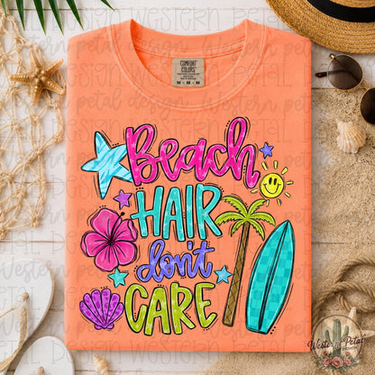 Folded neon cantaloupe Comfort Colors 1717 shirt with colorful “Beach Hair Don’t Care” tropical graphic in a coastal beach flat lay scene with shells, sunglasses, and straw hat.