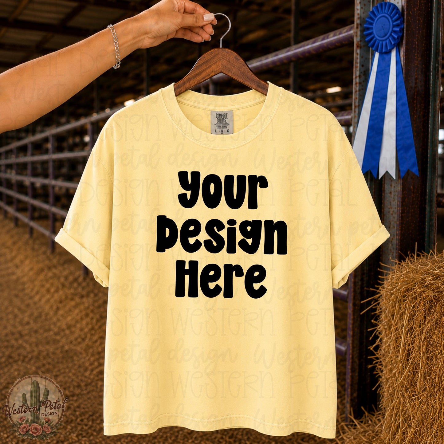 Comfort Colors 1717 Butter t-shirt mockup hanging on wooden hanger in livestock barn with blue ribbon and hay bale background.
